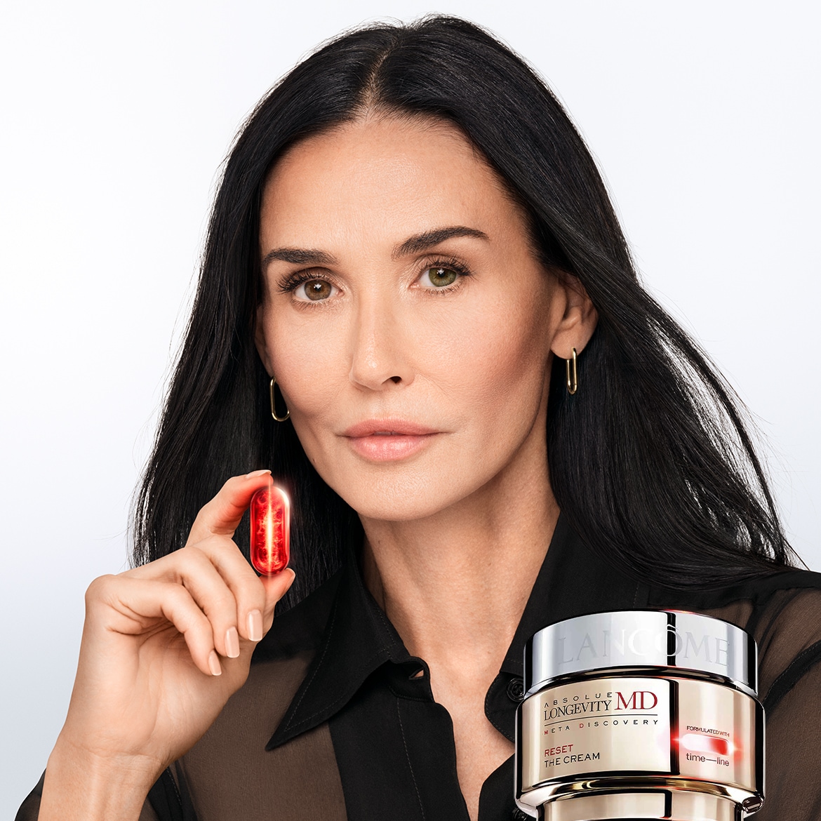 Primo piano di Demi Moore che tiene in mano una capsula rossa di Lancôme Absolute Longevity MD, con il vasetto di crema in primo piano, parte della linea Meta Discovery.