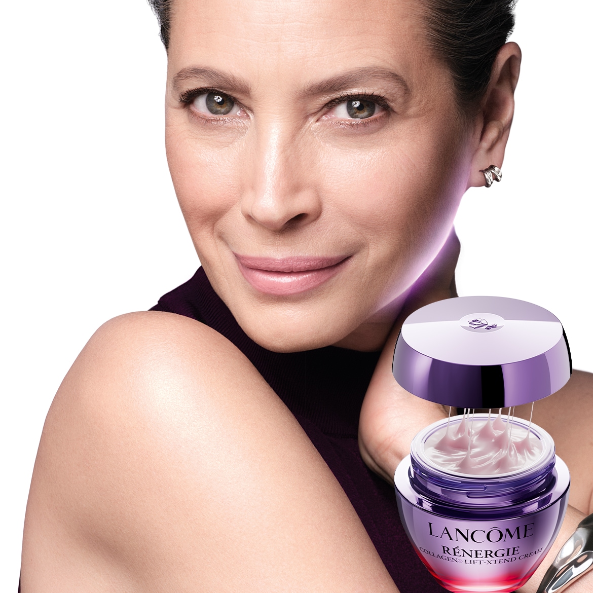 Primo piano di una donna che sorride con un vasetto aperto di crema Lancôme Rénergie Collagen Lift Xtend Cream, dalla confezione viola e rosa, che promette di liftare e rassodare la pelle.