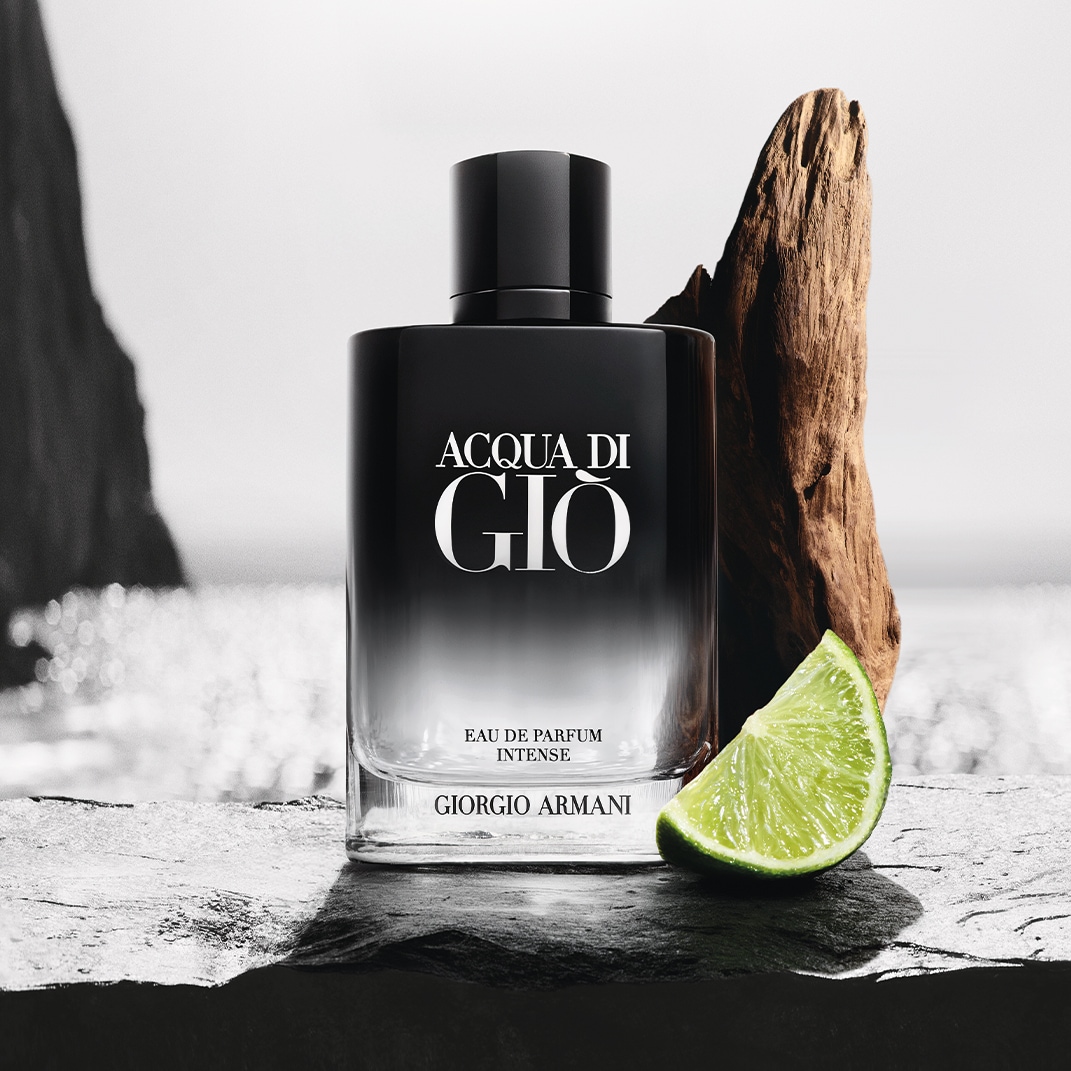 Ecco Acqua di Giò Eau de Parfum Intense di Giorgio Armani, una fragranza in una bottiglia nera sfumata con una fetta di lime verde brillante e un pezzo di legno sullo sfondo.