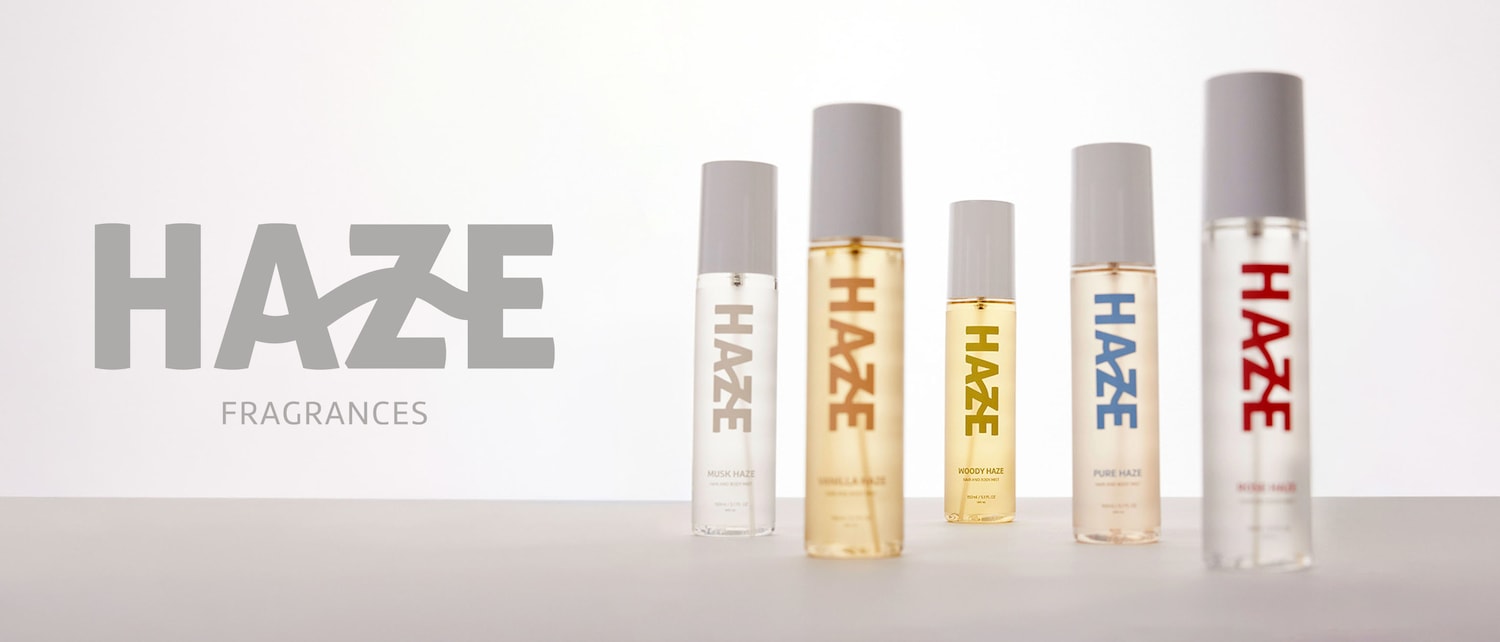 Esplora la collezione di fragranze Haze, ognuna in flaconi trasparenti con tappi grigi e etichette colorate che indicano il profumo: Musk, Vanilla, Woody, Pure e Rose.