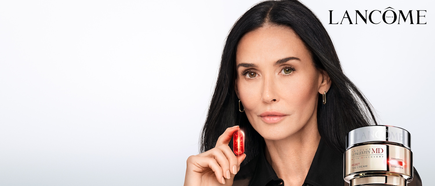 Primo piano di Demi Moore che tiene in mano una capsula rossa di Lancôme Absolute Longevity MD, con il logo del marchio in alto a destra e il barattolo di crema in basso a destra.