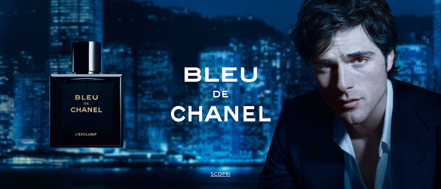 Scopri Bleu de Chanel L'Exclusif, una fragranza sofisticata in un flacone blu notte, presentata con un uomo elegante sullo sfondo di una città illuminata.