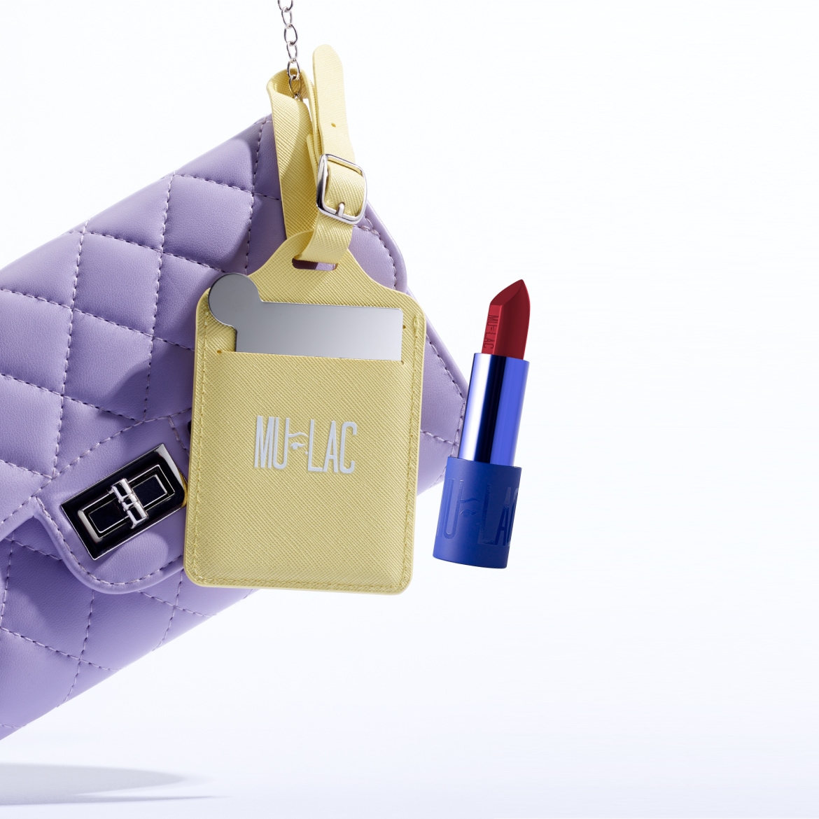 Borsa trapuntata color lavanda con etichetta gialla MU-LAC e rossetto rosso intenso con confezione blu.
