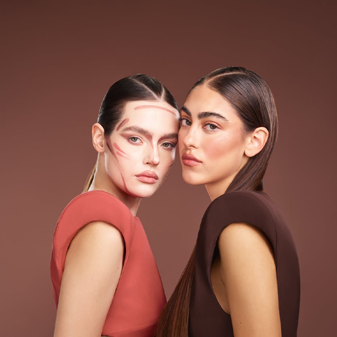 Due donne con contouring sul viso, una con abito corallo e l'altra marrone, incarnano l'arte del make-up.