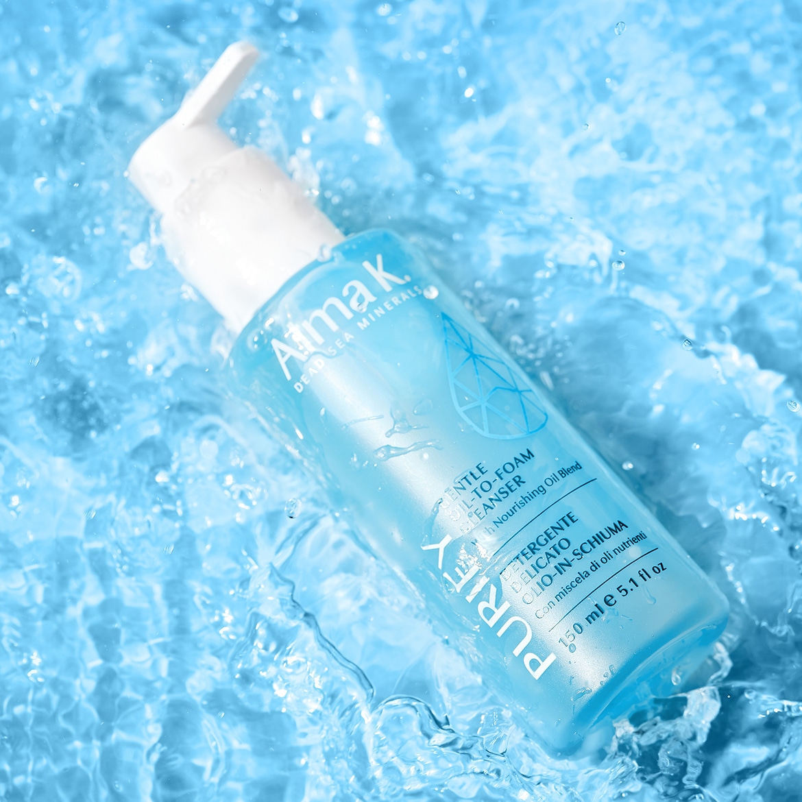 Ecco il detergente delicato olio-in-schiuma Alma K Dead Sea Minerals, arricchito con un mix di oli nutrienti, in un flacone azzurro trasparente da 150 ml, immerso in un fresco letto d'acqua.