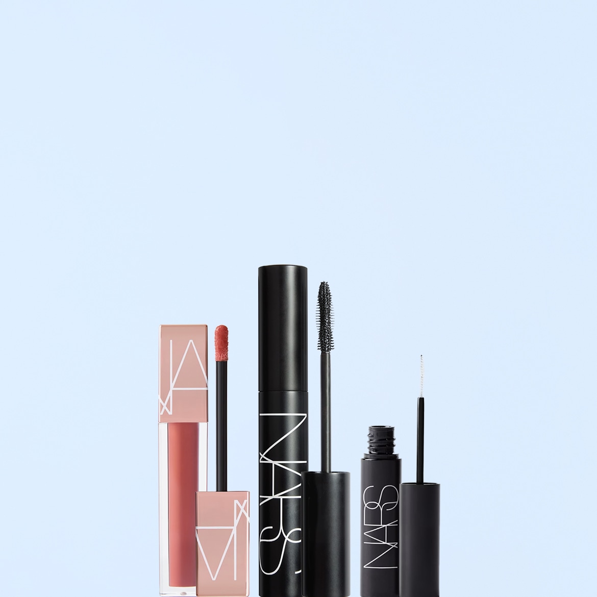 Un set di prodotti NARS, tra cui un lucidalabbra rosa pesca, un mascara nero e un eyeliner nero, sono disposti verticalmente su uno sfondo azzurro.