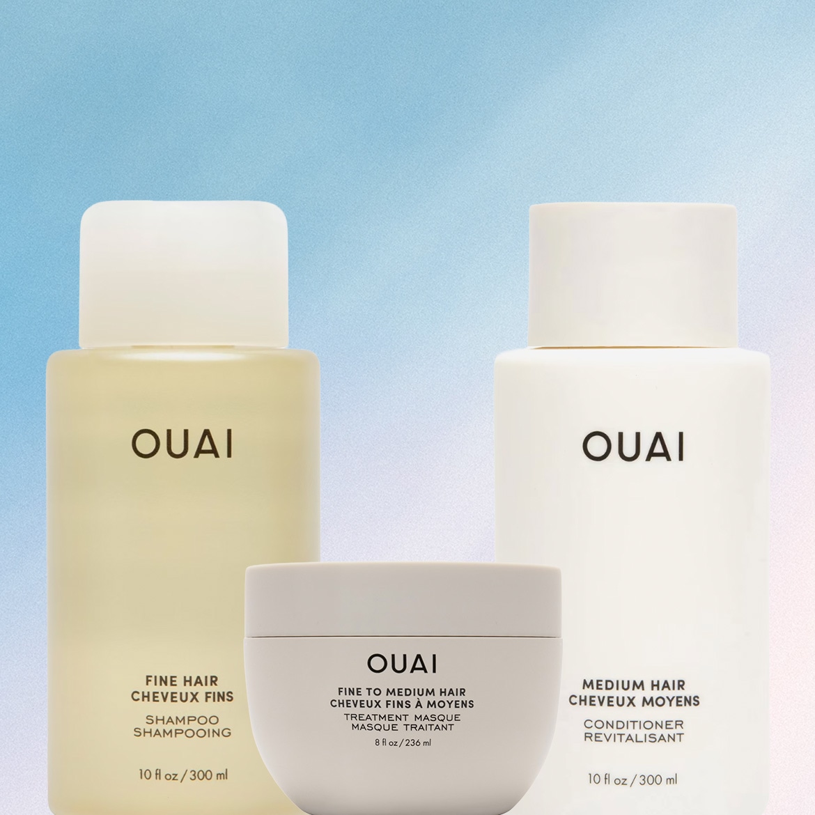Un set di prodotti per capelli OUAI, con uno shampoo per capelli fini, un balsamo per capelli medi e una maschera per capelli da fini a medi, tutti in eleganti flaconi bianchi e trasparenti.