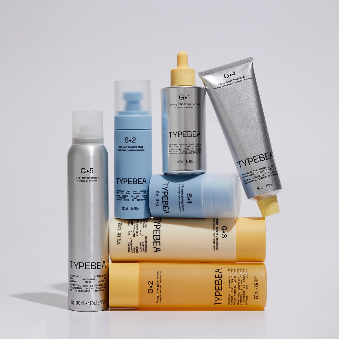 Una pila di prodotti Typebea per la cura dei capelli, tra cui shampoo secco, spray texturizzante al sale marino, peptide booster notturno, siero styling, shampoo e balsamo.