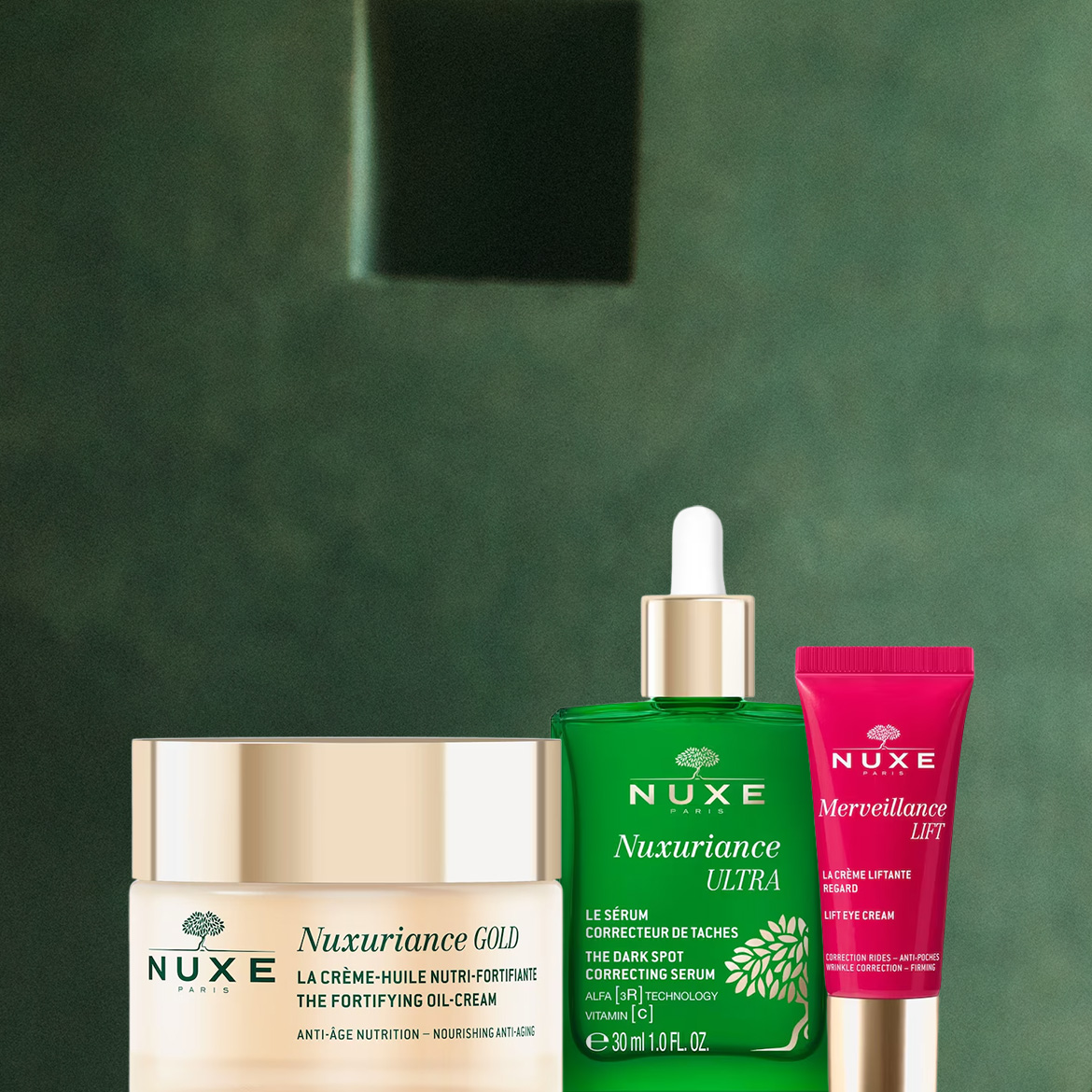 Tre prodotti Nuxe sono esposti su uno sfondo verde scuro: una crema Nuxuriance Gold in un vasetto color oro, un siero Nuxuriance Ultra in una bottiglia verde con contagocce e una crema occhi Merveillance Lift in un tubetto rosa.
