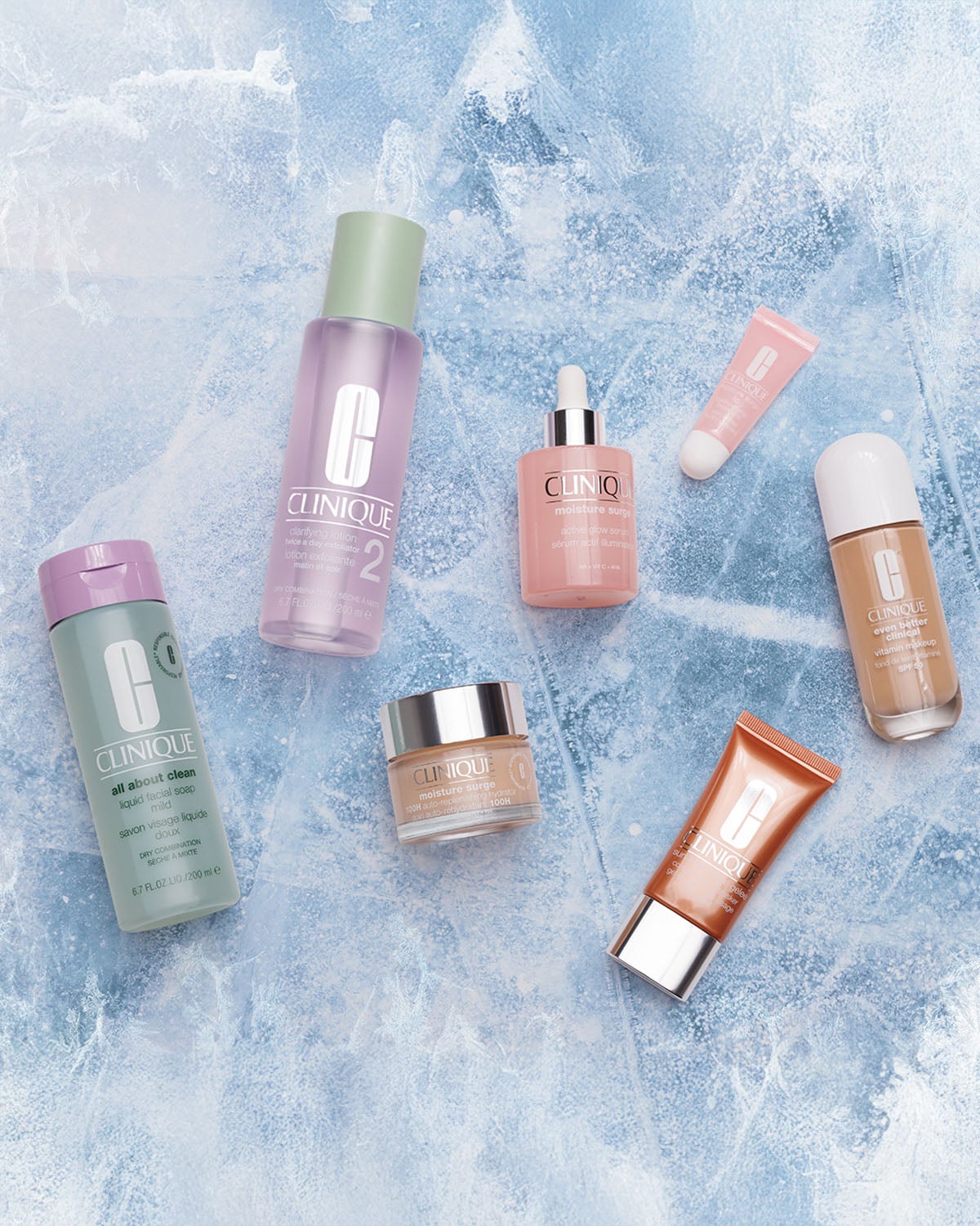 Una varietà di prodotti Clinique su sfondo blu screziato, tra cui detergente liquido delicato, lozione esfoliante, siero attivo illuminante, crema idratante e fondotinta con SPF.