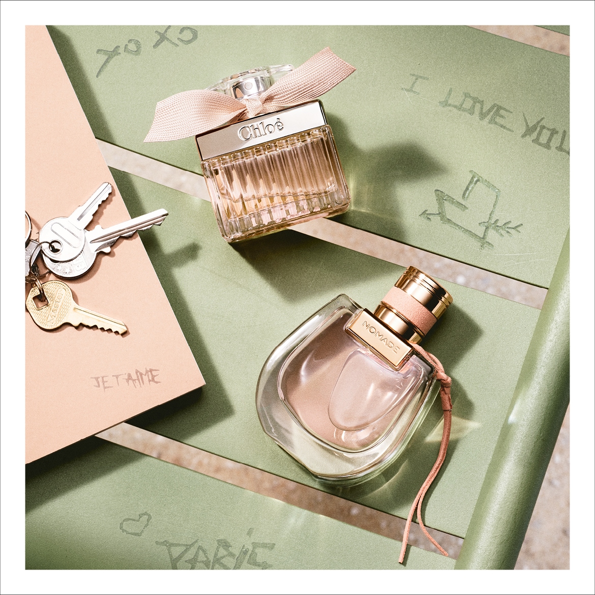 Due flaconi di profumo Chloé su sfondo verde pastello con scritte romantiche, uno classico con fiocco rosa e l'altro Nomade con dettagli in pelle.