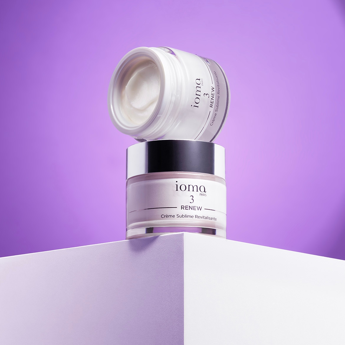 Ecco Ioma Paris 3 Renew Crème Sublime Revitalisante, due barattoli impilati su una superficie bianca, il barattolo superiore aperto mostra la crema bianca.