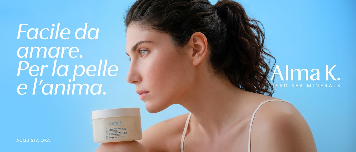 Against a serene blue backdrop, a woman with dark hair gazes pensively, next to Alma K. body scrub, with the phrase 'Easy to love. For the skin and soul.' and 'Buy Now'.