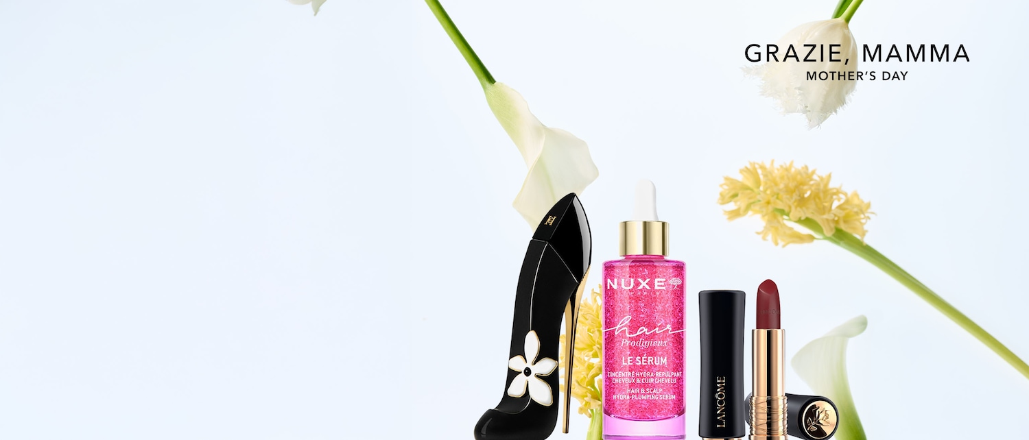 Celebra la Festa della Mamma con un'elegante composizione che include un profumo a forma di scarpa nera con decoro floreale, un siero rosa Nuxe e un rossetto Lancôme bordeaux.