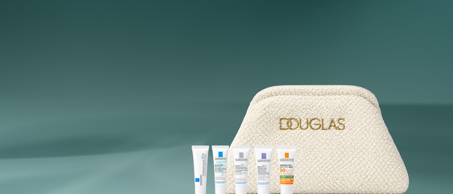 Una pochette Douglas color crema con quattro prodotti La Roche-Posay: Cicaplast Baume B5+, Effaclar Duo+M, Hyalu B5 e Anthelios UVMune 400, tutti in tubetti bianchi con dettagli blu, grigi, viola e arancioni, su uno sfondo verde acqua.
