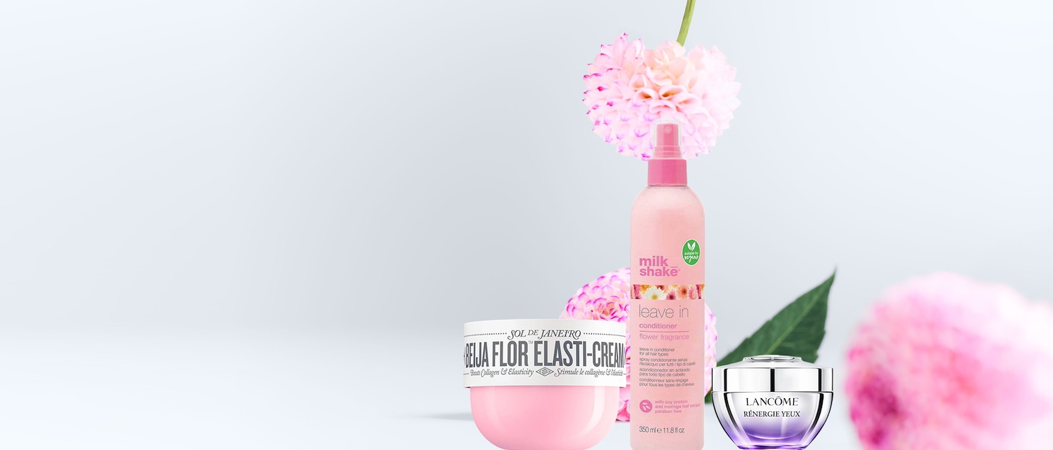 Ecco un trio di prodotti di bellezza: una crema rosa Sol de Janeiro, un balsamo spray Milk Shake e una crema occhi Lancôme, tutti in confezioni dai toni pastello.