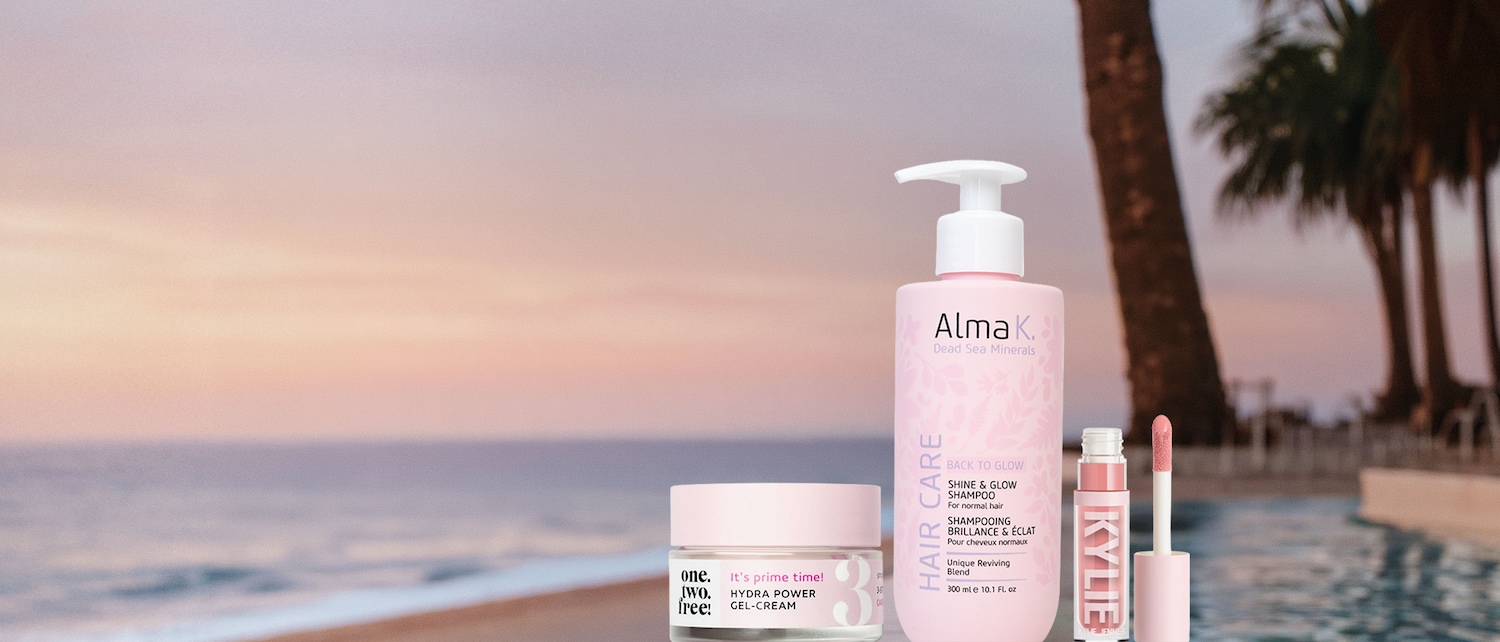 Una crema gel idratante One.Two.Free! Hydra Power in un vasetto rosa chiaro con coperchio, posizionata su un tavolo di fronte a un tramonto sulla spiaggia.