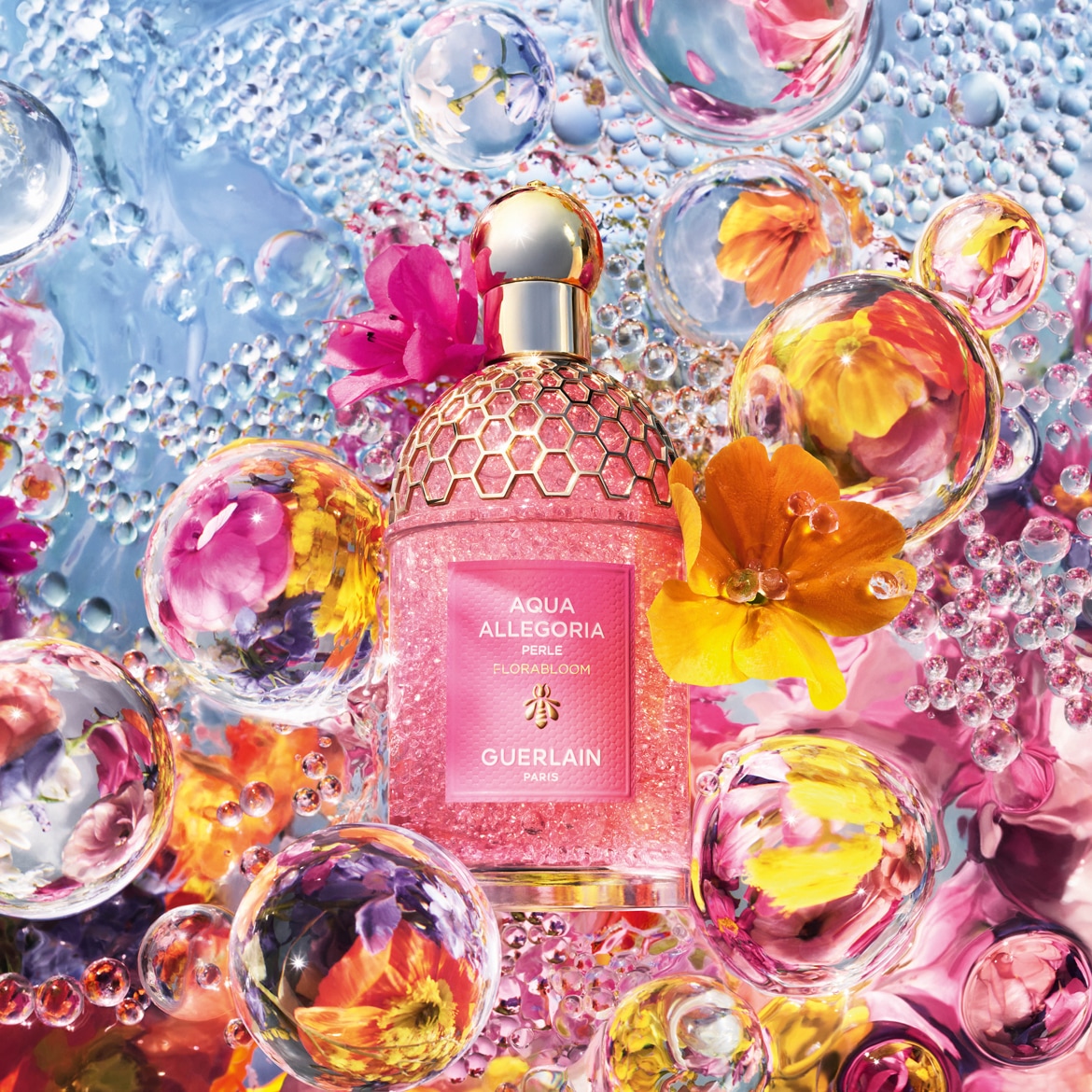 Il profumo Aqua Allegoria Perle Flora Bloom di Guerlain è presentato in un flacone rosa scintillante con tappo dorato, circondato da fiori colorati e bolle d'acqua.