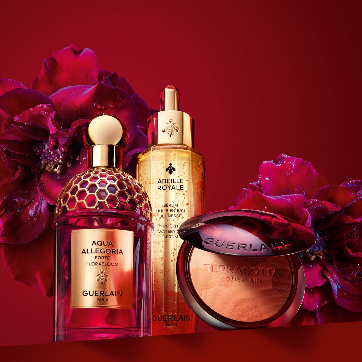 Esplora l'eleganza di Guerlain con Aqua Allegoria Forte Florabloom, Abeille Royale Youth Watery Serum e Terracotta bronzer, presentati su uno sfondo rosso intenso con rose scure.
