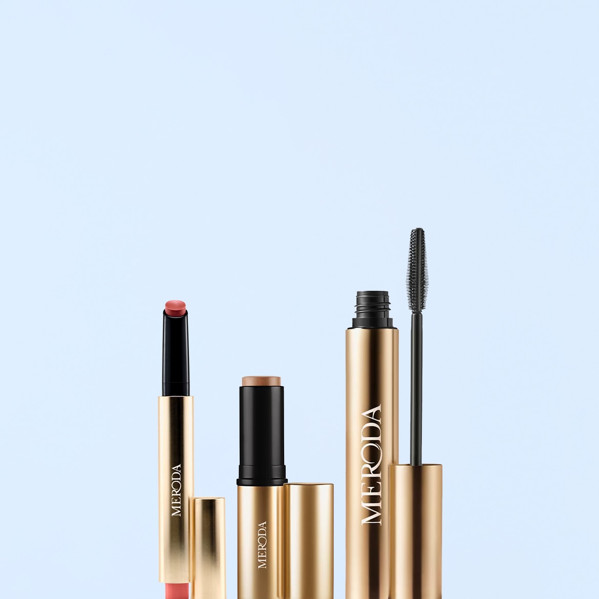 Un rossetto color pesca, un fondotinta a stick e un mascara nero, tutti con confezione dorata e il marchio "MERODA" in nero, sono disposti verticalmente su uno sfondo azzurro.
