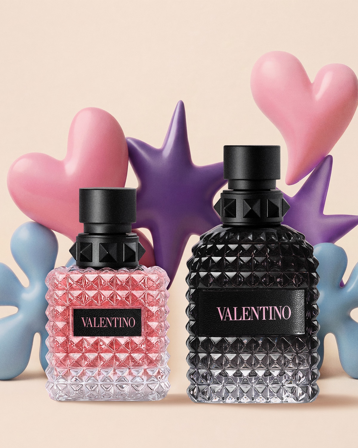 Due flaconi di profumo Valentino, uno rosa e uno nero, con decorazioni a forma di cuore e stella sullo sfondo.