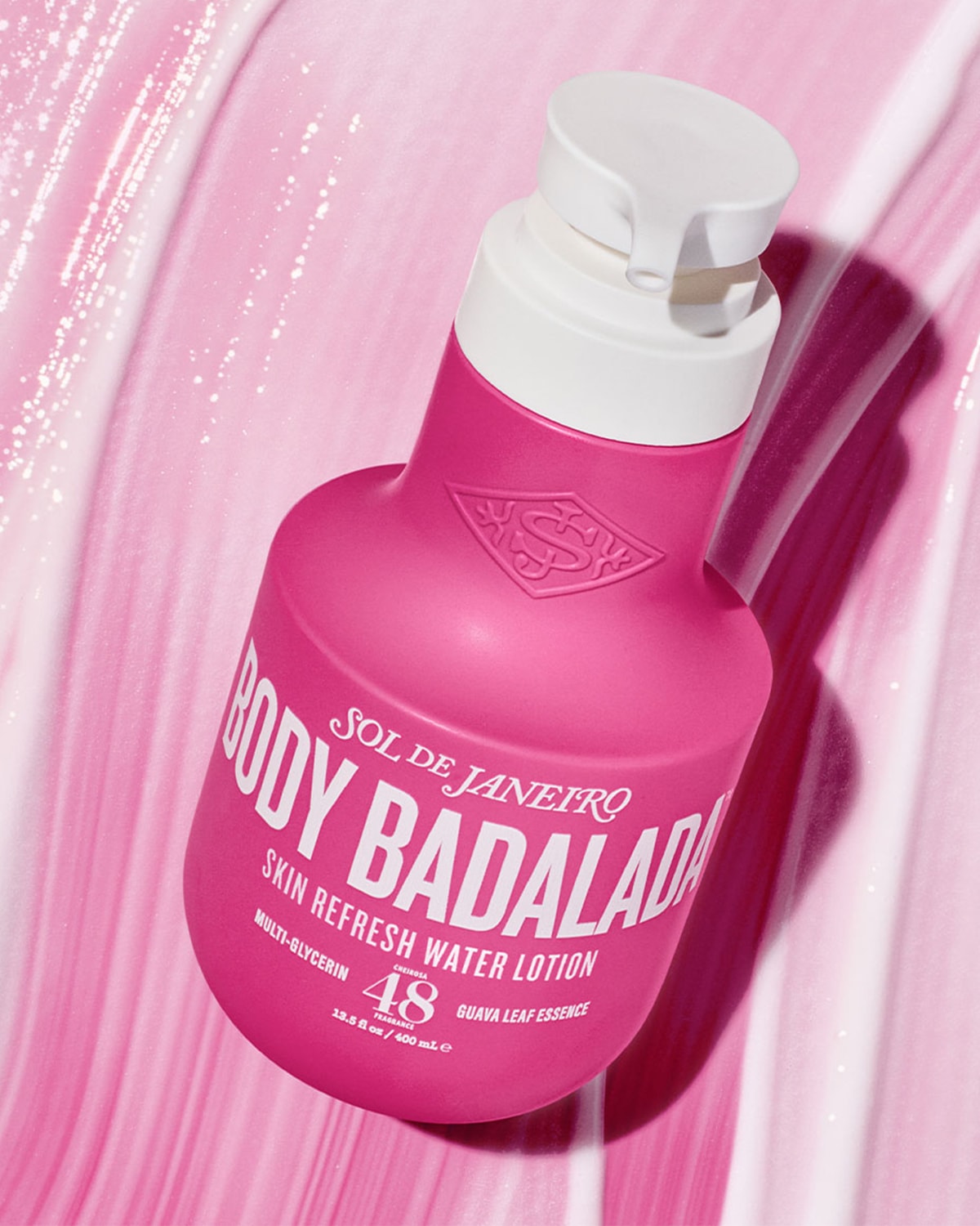 Ecco il flacone rosa di Sol de Janeiro Body Badalada Skin Refresh Water Lotion, con scritte bianche e tappo dosatore bianco, su uno sfondo rosa lucido.