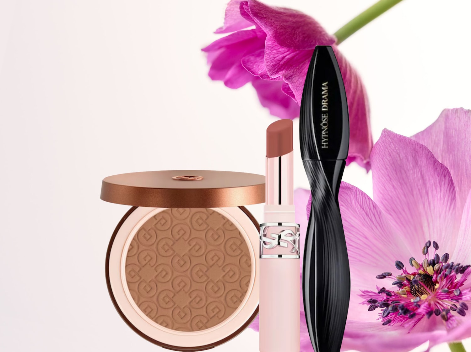 Un trio di prodotti beauty essenziali: una cipria compatta abbronzante con packaging dorato, un rossetto nude con logo argento e un mascara nero Hypnôse Drama, il tutto su uno sfondo floreale.