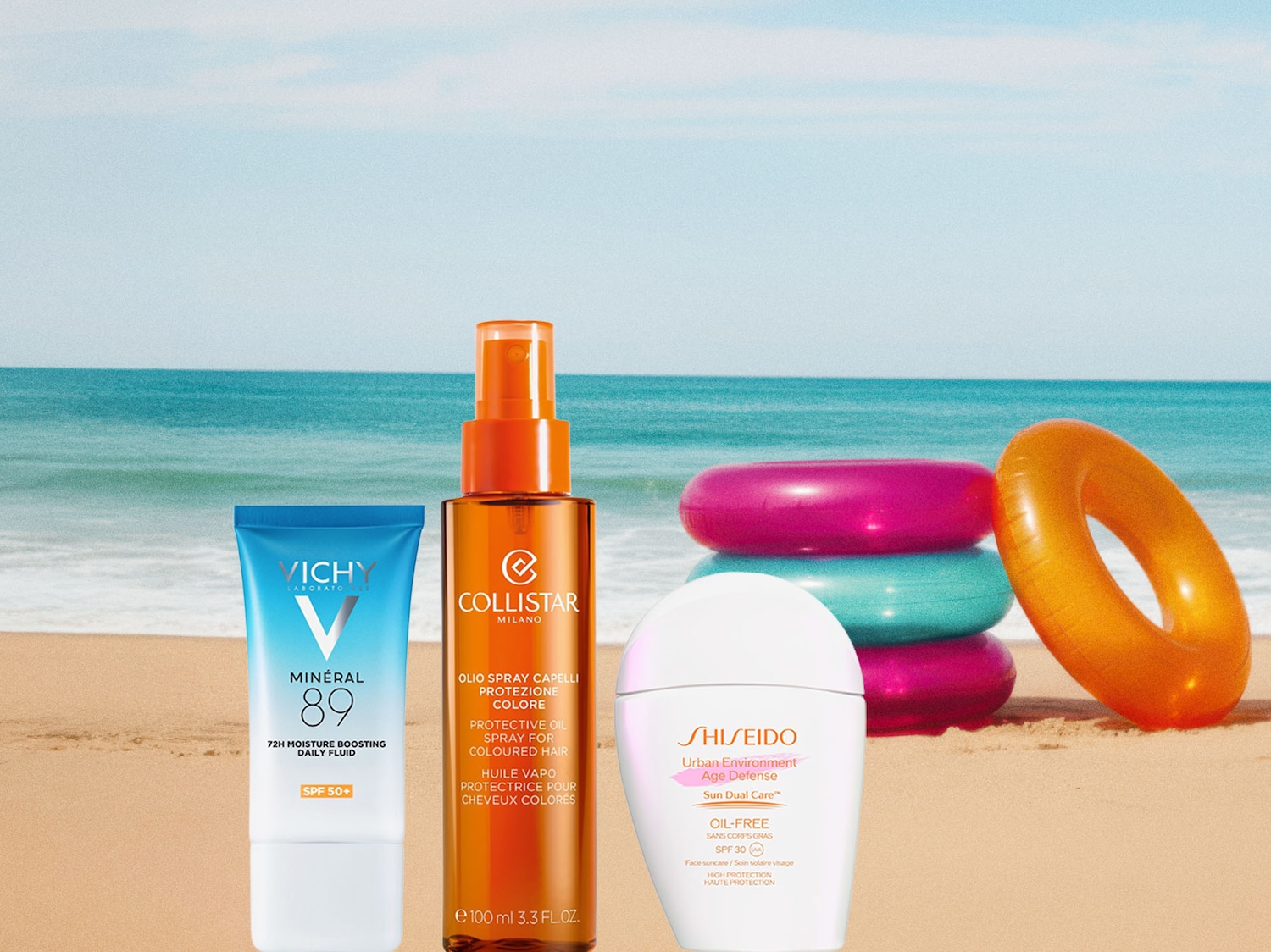 Sullo sfondo di una spiaggia assolata, spiccano i prodotti solari: Vichy Mineral 89, Collistar Olio Spray Capelli e Shiseido Urban Environment Age Defense.