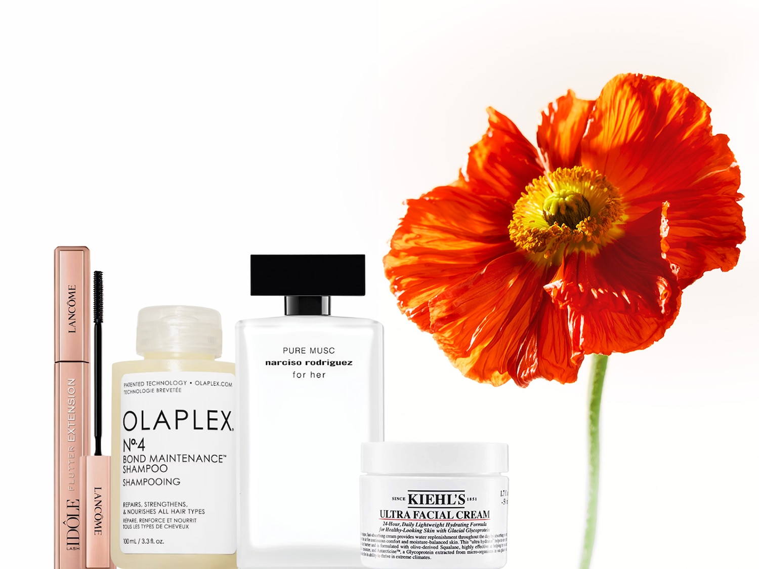 Un'esplosione di bellezza con mascara Lancôme Idôle Flutter Extension color pesca, shampoo Olaplex n.4, profumo Narciso Rodriguez Pure Musc e crema viso Kiehl's Ultra Facial Cream, accanto a un papavero arancione.
