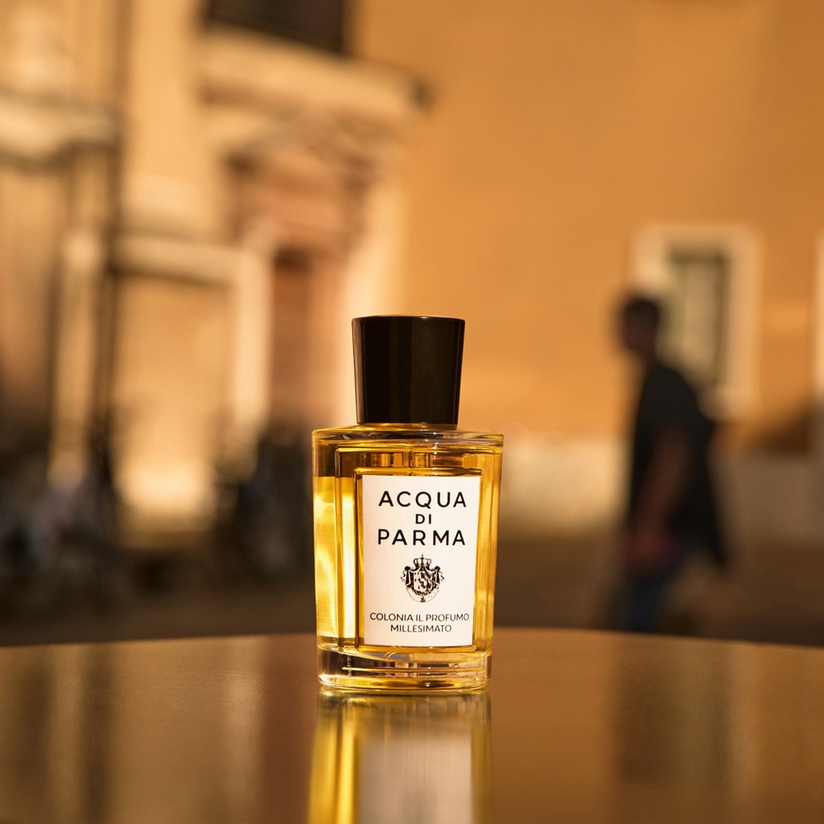 Ecco Acqua di Parma Colonia il Profumo Millesimato, una fragranza dorata in una bottiglia squadrata con tappo nero, che evoca l'eleganza italiana.